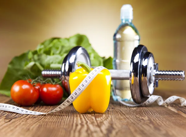 Vegetales frescos, mancuerna, cinta métrica y agua: alimentación saludable y actividad física